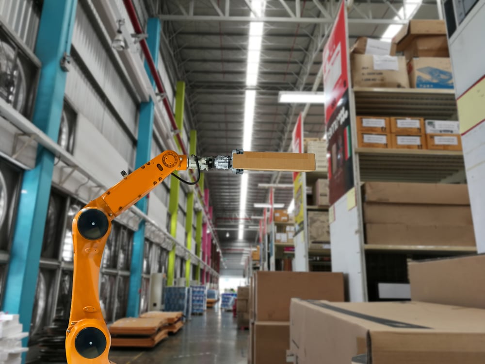 An innovative supply chain tech robot arm moving a package in a warehouse