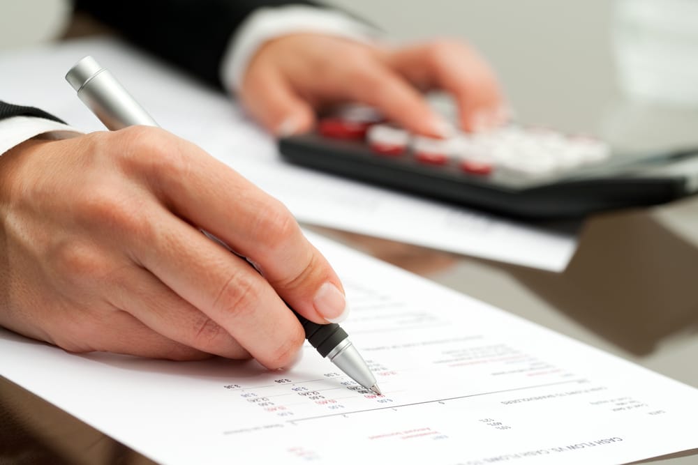 A close-up of a businessperson with calculator and budget spreadsheet